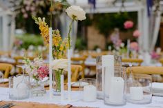 the table is set with candles, flowers and vases for an elegant wedding reception