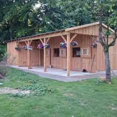 a large wooden building sitting in the middle of a lush green field