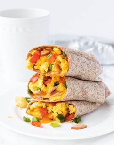 two burritos stacked on top of each other on a plate with a cup in the background