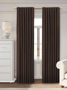 a living room with white furniture and brown curtains