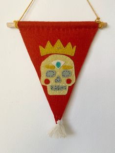 a wall hanging with a red triangle shaped banner and a gold crown on it's head