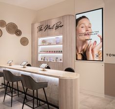 the nail bar has several chairs around it and there is a large advertisement on the wall