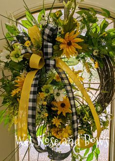 a wreath with sunflowers, daisies and greenery on it in front of a door