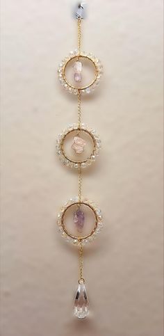 the three tiered necklace is adorned with pearls and pink stones, which are hanging from a gold chain