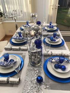 the table is set with silver and blue dishes