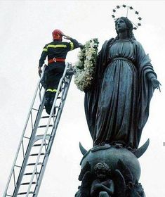 a man standing on top of a ladder next to a statue with flowers in it