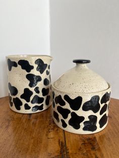 two black and white vases sitting on top of a wooden table