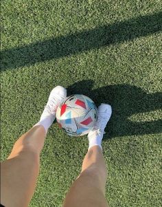 a person standing on top of a lush green field holding a soccer ball in their hands