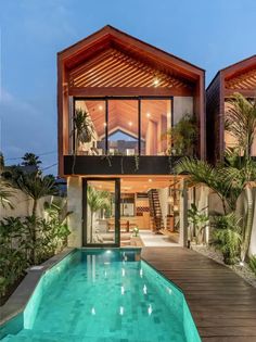 an outdoor swimming pool in front of a modern home with wooden floors and large windows