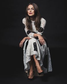 a woman sitting on top of a chair wearing a dress