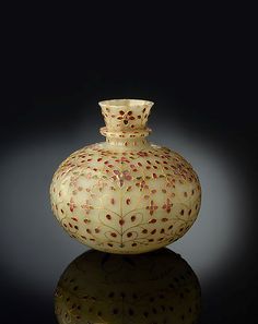 a white vase sitting on top of a reflective surface