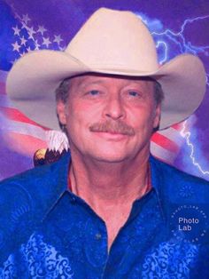 a man wearing a cowboy hat in front of an american flag