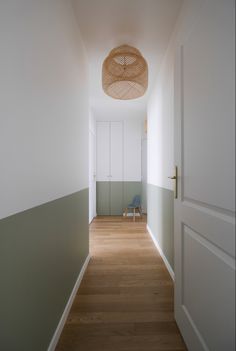 an empty hallway with a wicker basket hanging from the ceiling and wooden flooring