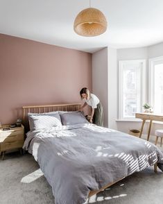 a woman standing on the edge of a bed in a bedroom