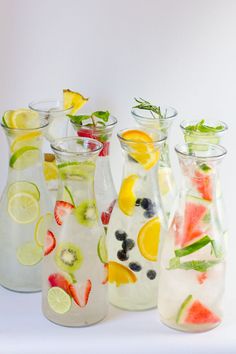 four glass vases filled with different types of fruit