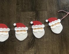 felt santa hats and stockings hanging from a string on a wooden table with candy canes