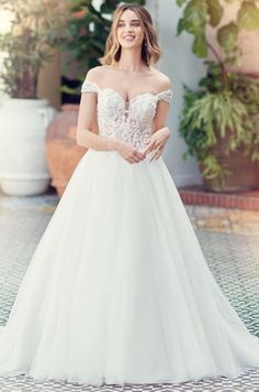 a woman in a white wedding dress standing on a tiled floor next to potted plants