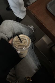 a person sitting down with a cup of coffee in their hand and a straw sticking out of it