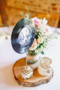 there is a vase with flowers in it and an old record on the table top