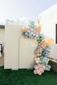 a balloon arch is decorated with pastel colors