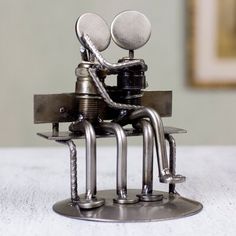 a metal figurine sitting on top of a table with two spoons in it