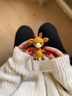 a person holding up a tiny giraffe toy in their hands, with red nails