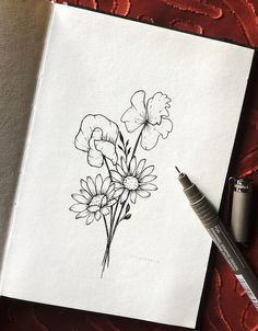 a drawing of some flowers on a piece of paper next to a marker and pen