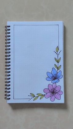 a notebook with flowers painted on the cover and lined in paper, sitting on a table