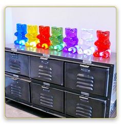 an assortment of colorful gummy bears on top of a black cabinet with drawers and doors