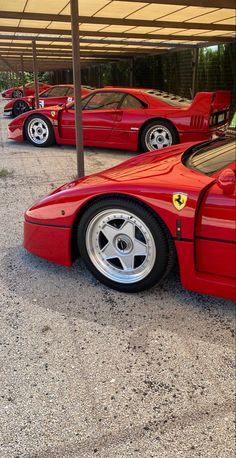 three red sports cars parked in a parking lot next to each other under a canopy