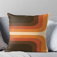 an orange and brown throw pillow sitting on top of a couch