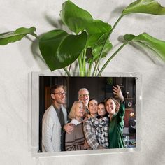 a group of people standing next to each other in front of a plant