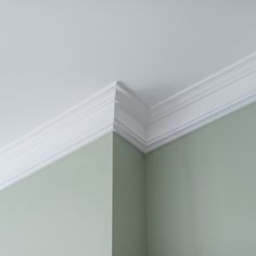 the corner of an empty room with green walls and white trim on the ceiling,