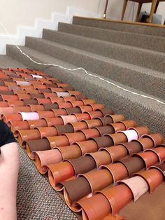 a man sitting on the ground next to some brown and red tiles in front of stairs