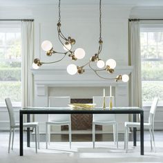 a dining room table with chairs and a chandelier hanging from it's ceiling