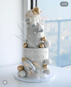 a three tiered cake decorated with silver and gold decorations on top of a white table