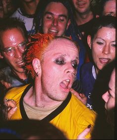 a man with red hair sticking out his tongue in front of a group of people