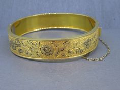 Gorgeous Victorian revival antique bangle.  Has a box clasp that works great and fixed safety chain.  Signed 1/20th 10k gold filled.  Visit Ribbons Edge for more great pieces of vintage and antique jewelry!  All items added to your cart at Ribbons Edge will automatically combine shipping. To stay up to date with my newest offerings, follow me on IG @ RibbonsEdge Victorian Gold Hinged Bangle, Gold Victorian Hinged Bangle, Vintage Yellow Gold Cuff Bracelet For Ceremonial Occasions, Victorian Etched Gold Bangle, Victorian Gold Bangle Bracelet For Ceremonial Occasions, Gold Etched Victorian Bangle, Victorian Gold Hallmarked Bangle, Victorian Style Gold Hallmarked Bangle, Antique Yellow Gold Cuff Bracelet For Ceremonial Occasions