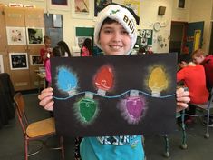 a young boy holding up a chalkboard with lights on it in front of him