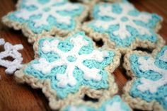 four crocheted snowflakes sitting on top of a wooden table