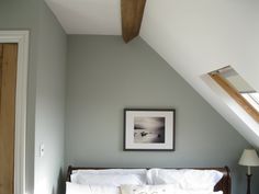 a bed with white linens in a bedroom under a slanted ceiling