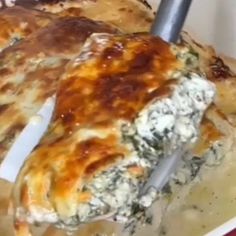 a pizza with cheese and spinach on it is being cut by a spatula