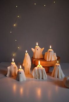 some white candles with ghost faces and lights in the middle are sitting on a table