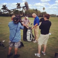 a group of men standing on top of a lush green field next to a golf bag