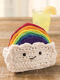 a crocheted pot holder with a rainbow on it and a lemon in the background