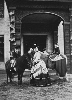 an old black and white photo of a woman on a horse in front of a building