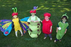 three children dressed in costumes standing on the grass