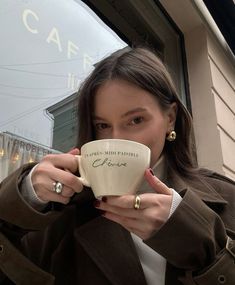 a woman is holding a coffee cup in her hands