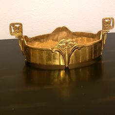 a gold plate sitting on top of a wooden table next to a white wall and black floor