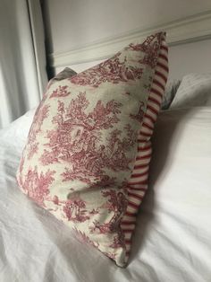 a red and white pillow sitting on top of a bed